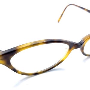 May include: A pair of eyeglasses with a tortoiseshell pattern. The frames have a cat-eye shape with a dark brown and yellow color scheme. The temples are thin and extend to the ear. The lenses are clear.