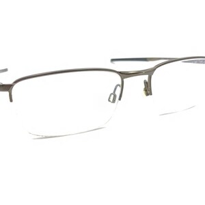 May include: A pair of silver-toned metal spectacles with a half-rim design and clear lenses.