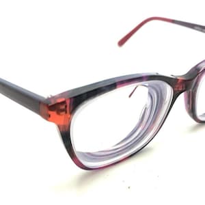 May include: Eyeglasses featuring a translucent frame with a marbled pattern in shades of purple, black, and red. The glasses have clear lenses and dark, solid-colored temples that transition to a reddish hue at the tips, providing a distinct look.