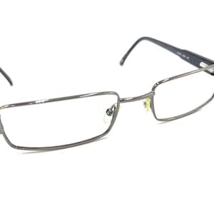 Puede incluir: Un par de gafas de metal plateado con lentes rectangulares. Las gafas tienen un diseño simple y moderno.