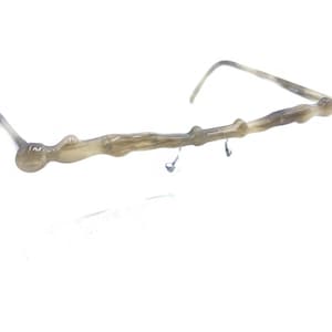 Puede incluir: Un par de gafas con un marco único de forma orgánica, hecho de plástico marrón claro.