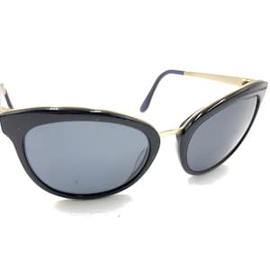 May include: Black cat-eye sunglasses with gold metal accents and dark gray lenses.