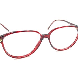 May include: Red tortoiseshell eyeglasses with gold accents. The glasses have a rounded, oval shape.