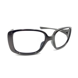 May include: A pair of dark charcoal gray eyeglasses with a glossy finish. The frames feature a wide, rectangular shape with rounded corners and integrated nose pads. The temples are thin and extend from the outer edges of the frame front.