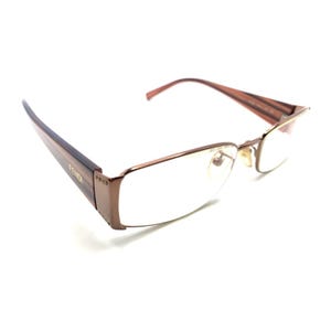 May include: Fendi eyeglasses featuring a rectangular frame in a metallic brown finish. The temples display a striped pattern in shades of brown and tan with the Fendi logo printed on the side. The bridge includes adjustable nose pads.