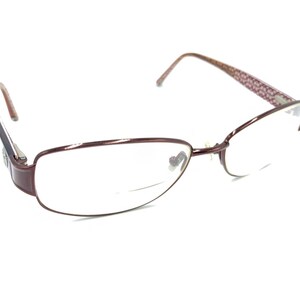 May include: Burgundy-colored metal eyeglasses with a rimless design and clear lenses.