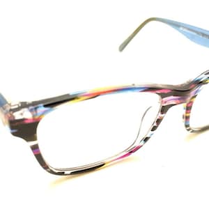 May include: Cat-eye eyeglasses with a colorful, abstract pattern on the frames. The frames feature a mix of colors including blue, pink, yellow, and black. The temples are a solid blue color.