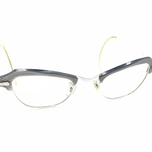 Puede incluir: Un par de gafas vintage de ojo de gato con montura azul oscuro y lentes transparentes.