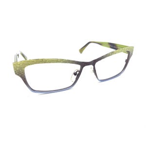 Puede incluir: Gafas con montura de ojo de gato que presentan un degradado de color desde el verde lima en la parte superior hasta el morado oscuro en la inferior. La superficie de la montura tiene un patrón texturizado de rayas. Las patillas son verde lima.