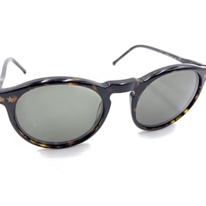 Puede incluir: Gafas de sol redondas de carey con lentes verdes y detalles de estrellas doradas.