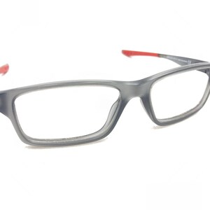 May include: Gray plastic framed eyeglasses with red accents on the arms.