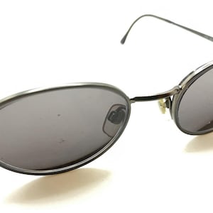 May include: Silver oval-shaped sunglasses with dark gray lenses.