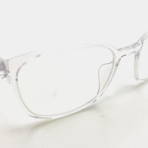 May include: Clear, transparent eyeglasses with a rectangular frame. The glasses have a subtle, minimalist design, with a focus on functionality and clarity. The frames are made of a lightweight material, and the lenses are clear.