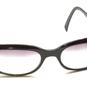 Puede incluir: Gafas de sol ovaladas negras con lentes degradados. Las gafas tienen un fino marco negro.