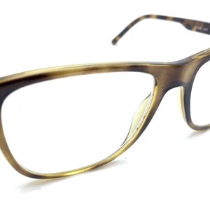 May include: Tortoiseshell eyeglasses featuring a classic rectangular frame design with a brown and tan mottled pattern. The glasses have clear lenses and thin, matching temples that extend from the sides of the frame, providing a clear view.