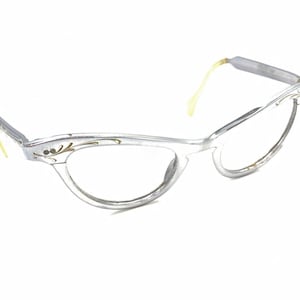 Puede incluir: Gafas de sol de ojo de gato plateadas con un diseño floral dorado en el marco.