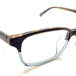 May include: Eyeglasses with a rectangular frame. The frames are a mix of brown and light blue, with a tortoise shell pattern on the arms. The lenses are clear, and the glasses are set against a white background.