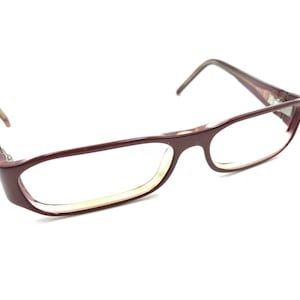 Pode incluir: Óculos de plástico cor de vinho com armação retangular e lentes transparentes.