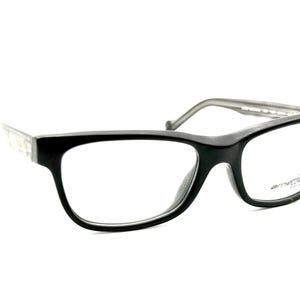 May include: Black eyeglasses with a rectangular frame and clear lenses. The temples are a light gray color with a patterned design. The brand name "Arnette" is visible on the lens.