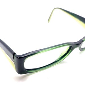 Può includere: Occhiali con montatura rettangolare caratterizzata da un esterno blu navy scuro e un interno verde lime brillante. Le aste sono blu navy scuro all'esterno e verde lime all'interno, con lenti trasparenti e naselli integrati.