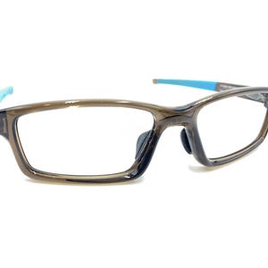 May include: A pair of brown eyeglasses with blue arms. The glasses have a rectangular frame and clear lenses.
