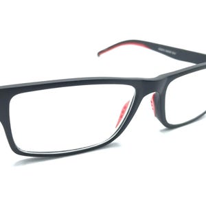 Puede incluir: Gafas rectangulares negras con detalles rojos en las patillas y almohadillas nasales. Las monturas son de color negro mate y las lentes son transparentes. Estas gafas son para la corrección de la visión.