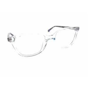 Peut inclure: Lunettes transparentes avec une monture de forme rectangulaire arrondie. Les branches présentent un motif écaille de tortue marron et noir. Le pont est incurvé et les charnières sont visibles sur les bords extérieurs de la monture.