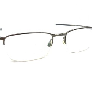 May include: A pair of silver-toned spectacles with a half-rim design. The glasses have a rectangular shape and clear lenses.