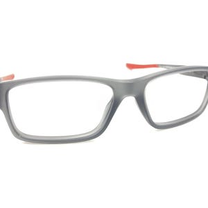 May include: Gray rectangular eyeglasses with red accents on the arms.