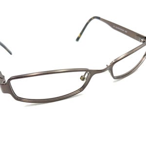 Puede incluir: Un par de gafas de metal marrón con montura rectangular.