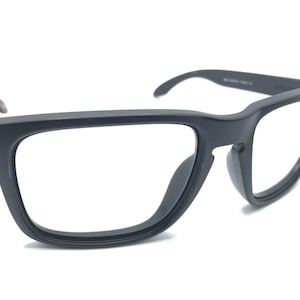 May include: Black plastic framed eyeglasses with clear lenses. The frame has a squared shape with rounded edges.