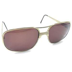 May include: Gold-tone aviator sunglasses with brown lenses. The sunglasses have a double bridge and a thin metal frame.