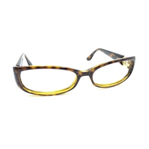 Può includere: Occhiali con montatura a fantasia tartarugata e bordo interno giallo. Gli occhiali hanno una forma rettangolare e un design classico. Le aste sono marrone scuro.