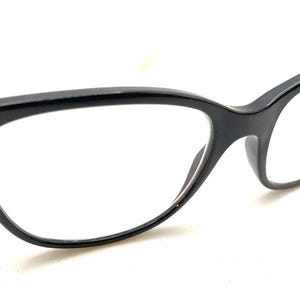 May include: A pair of black cat-eye glasses with a glossy finish. The frames feature a distinct upswept shape at the outer corners and thin, clear temples. The lenses are transparent and clear, showcasing the overall structure of the eyewear.