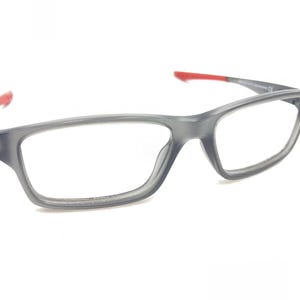 May include: Gray plastic framed eyeglasses with red accents on the arms.