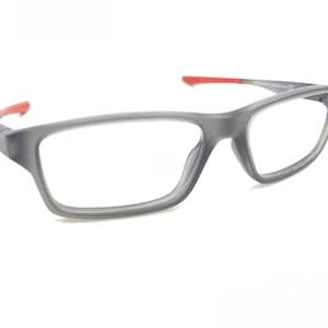 May include: Gray rectangular eyeglasses with red accents on the temples. The glasses have a matte finish and clear lenses. The frame is a medium gray color, and the overall design is modern and minimalist.