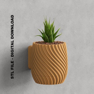 Op de afbeelding: Een bruine, getextureerde, wandgemonteerde plantenpot met een kleine vetplant erin. De pot heeft een golvend ontwerp en een kleine, witte beugel aan de achterkant.