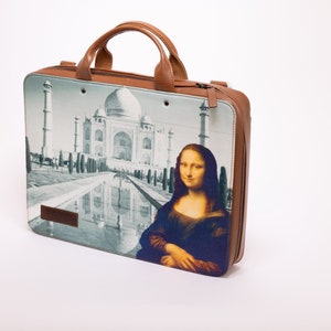 May include: A brown leather laptop bag with a zipper closure. The bag has a printed design featuring the Taj Mahal and the Mona Lisa.