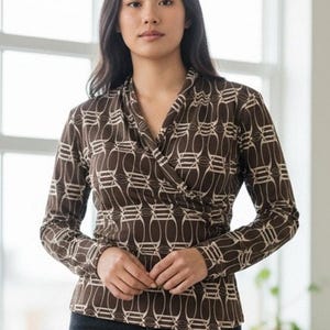 May include: A long-sleeved wrap top in a brown and cream geometric pattern. The top features a V-neckline and a fitted silhouette. The fabric has a soft, flowing appearance. The top is paired with dark-colored pants.