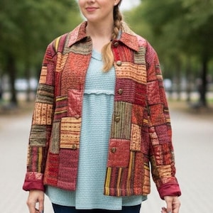 May include: A long-sleeve button-down jacket featuring a patchwork design with various textures and patterns in shades of red, orange, yellow, and brown. The jacket has a classic collar and is worn over a light blue textured shirt.