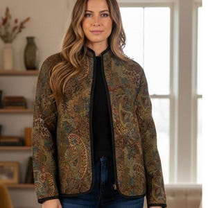 May include: A paisley-patterned jacket in shades of olive green, brown, and rust. The jacket has a black trim and a mandarin collar. The jacket is open in the front and appears to be made of a quilted material.
