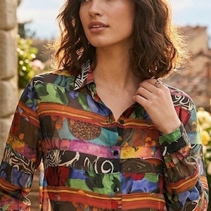 May include: A long-sleeved button-down shirt featuring a vibrant, multi-colored abstract print with horizontal bands of various patterns, including floral, geometric, and animal-inspired motifs in shades of green, blue, red, yellow, and black.