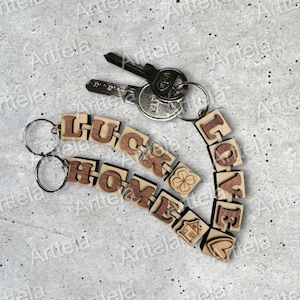 May include: A wooden keychain with the words "LUCK HOME LOVE" spelled out in individual blocks. The keychain is attached to a set of keys with a silver key ring.