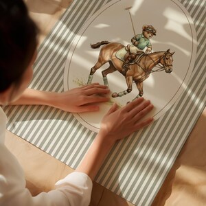 May include: An oval-shaped illustration of a teddy bear playing polo on a brown horse, set against a cream background. The bear wears a green polo shirt and riding gear. The illustration is on a striped, light green and white surface.