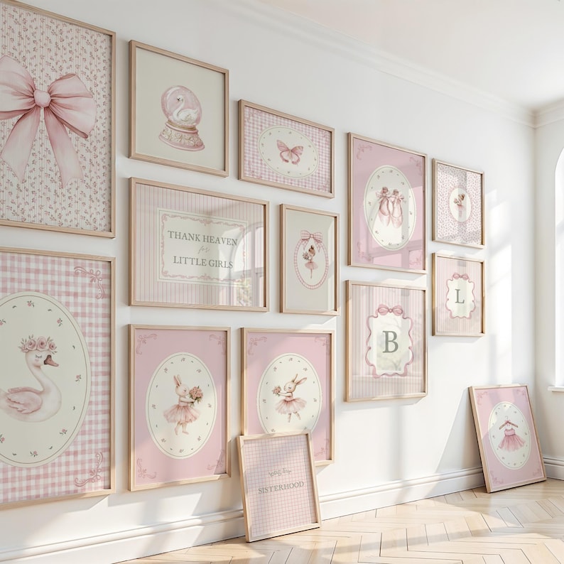 May include: A collection of framed wall art in shades of pink and white, featuring various designs such as a swan, a ballerina, a bow, and the text "Thank Heaven for Little Girls". The frames are light wood.