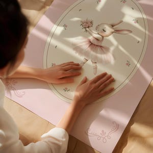 May include: A pink yoga mat featuring a ballerina bunny illustration. The bunny is wearing a pink tutu and holding a bouquet of flowers. The mat has a light pink background with floral and decorative accents.