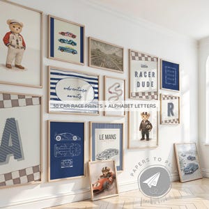 Puede incluir: Una colección de láminas enmarcadas con temas de carreras de coches y letras del alfabeto. Las láminas presentan coches de carreras, pistas de carreras y los textos "adventure awaits" y "Le Mans". También se muestra un oso de peluche con un traje de carreras.