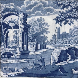May include: A blue and white toile napkin featuring a pastoral scene with figures, buildings, and trees. The design includes a bridge, a castle, and the word "Spode" in the lower left corner. The overall aesthetic is reminiscent of classic blue and white china.