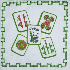 May include: A white square paper napkin featuring a green bamboo-style border. The center displays five Mahjong tiles arranged in a cross pattern. The central tile shows a panda holding bamboo with the text Joker, surrounded by four tiles.