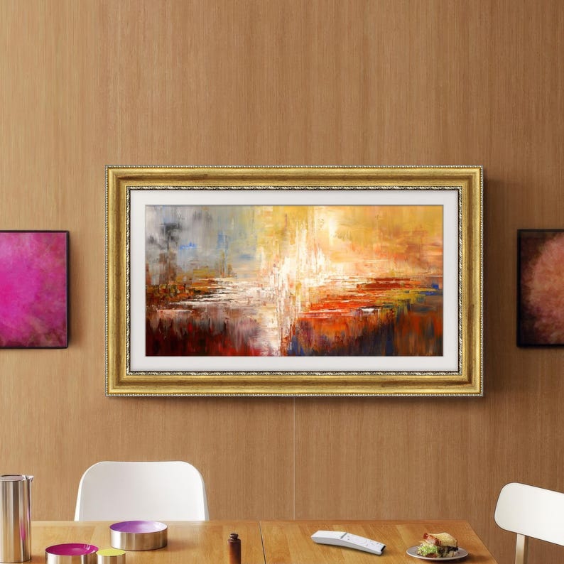 K&ouml;nnte beinhalten: Abstraktes Gem&auml;lde in einem goldenen Rahmen. Das Kunstwerk zeigt eine lebendige Mischung aus Farben, darunter Rot, Orange, Gelb, Blau und Wei&szlig;, wodurch eine strukturierte, landschafts&auml;hnliche Komposition entsteht. Das Gem&auml;lde wird an einer holzget&auml;felten Wand ausgestellt.